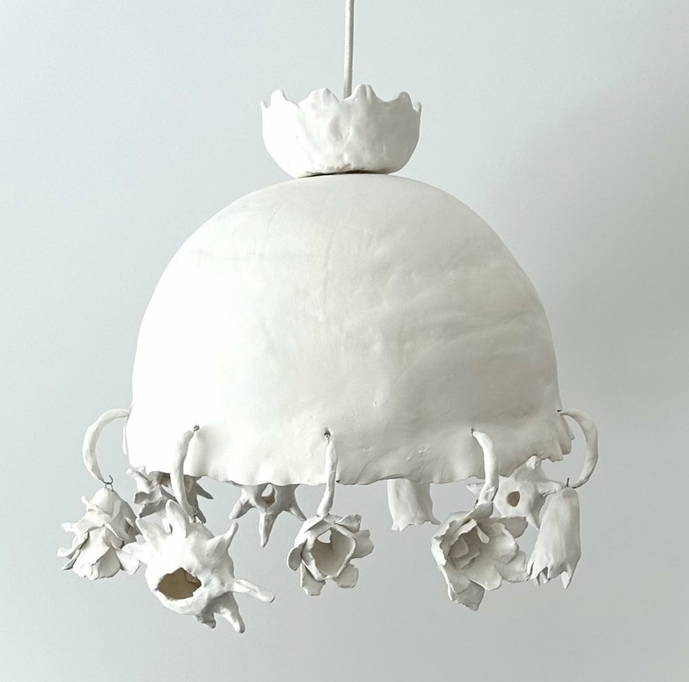 A white chandelier with flowersDescription automatically generated